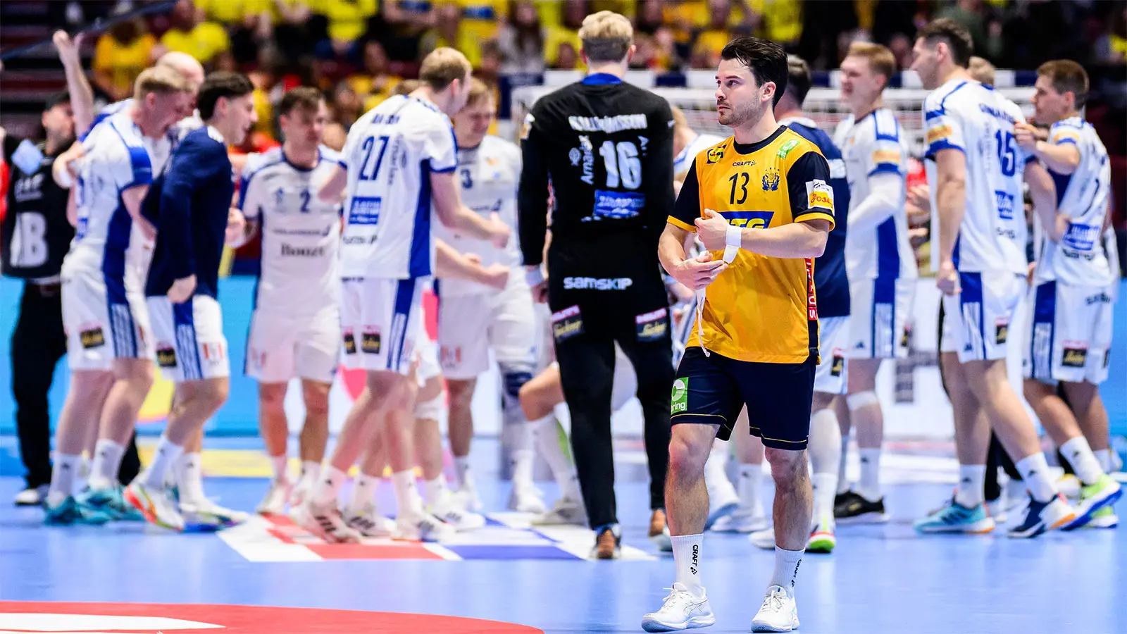Sebastian Karlsson från Sverige ser nedslagen ut efter matchen i huvudrundan mellan Island och Sverige den 25 januari 2026 i Malmö. I bakgrunden firar de Isländska spelarna vinsten. 