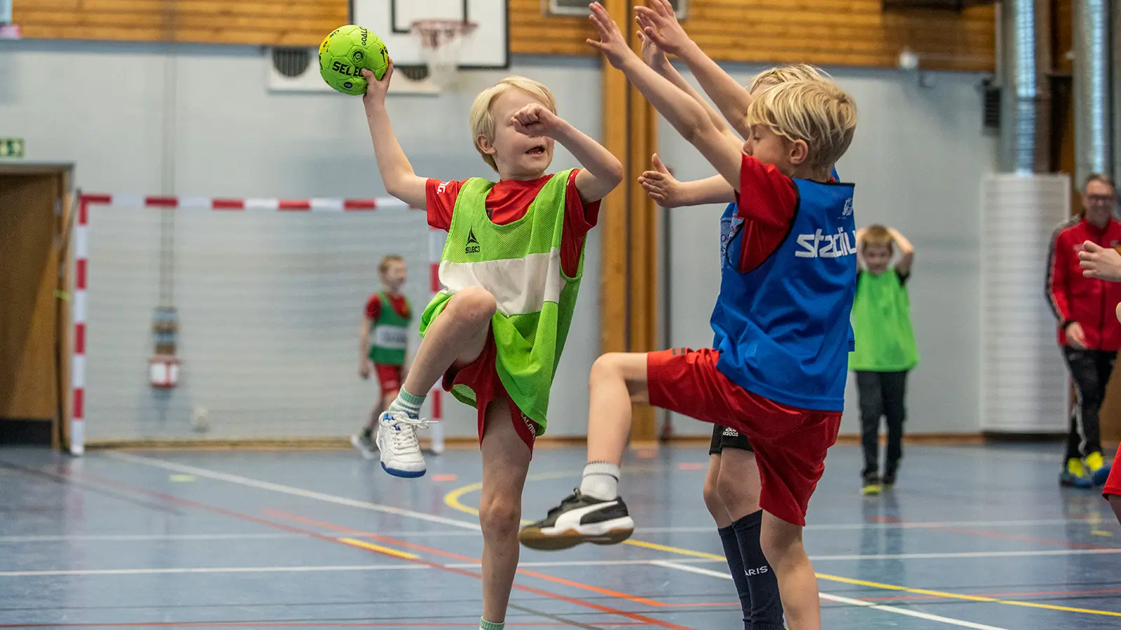 små killar som spelar handboll, en ska skjuta och en täcker med händerna rakt upp